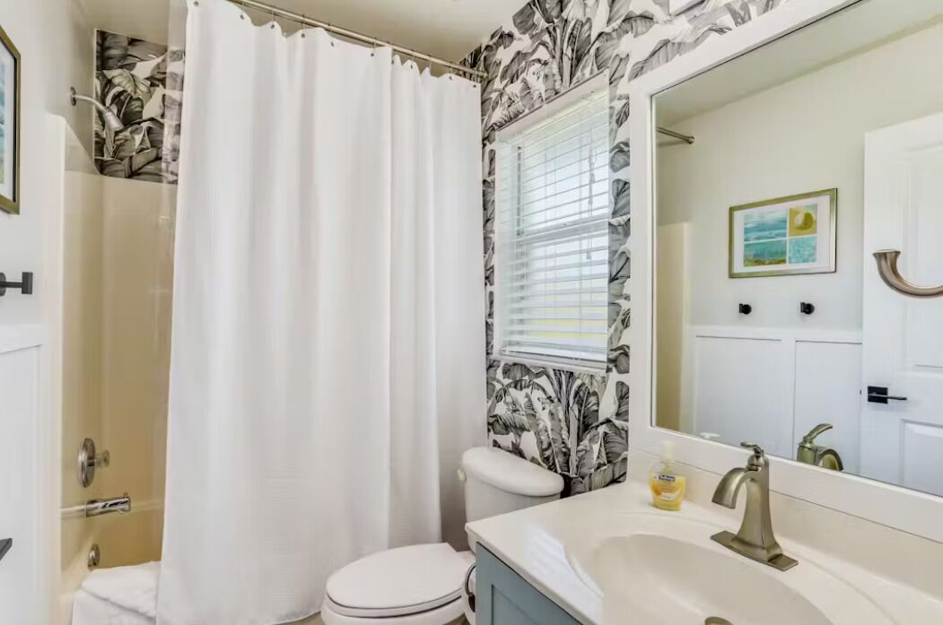 Een badkamer met toilet, wastafel en douchegordijn.