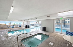 Un espace piscine comprenant un jacuzzi, des chaises longues et un panneau de sortie.