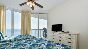 Un dormitorio con cama, cómoda, ventilador de techo y televisión.