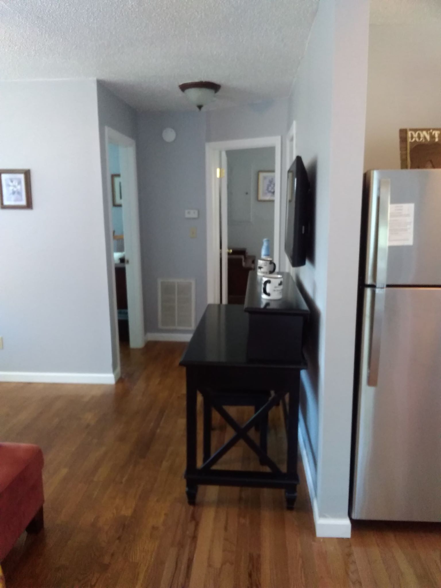 A kitchen with a refrigerator, a black table, and a microwave.