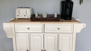 A kitchen area with a white cabinet, a toaster, a coffee maker, and a framed picture on the wall.