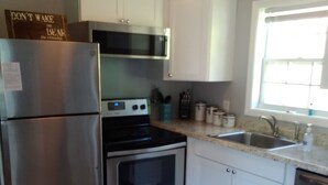 A compact kitchen with a refrigerator, stove, oven, and dishwasher.