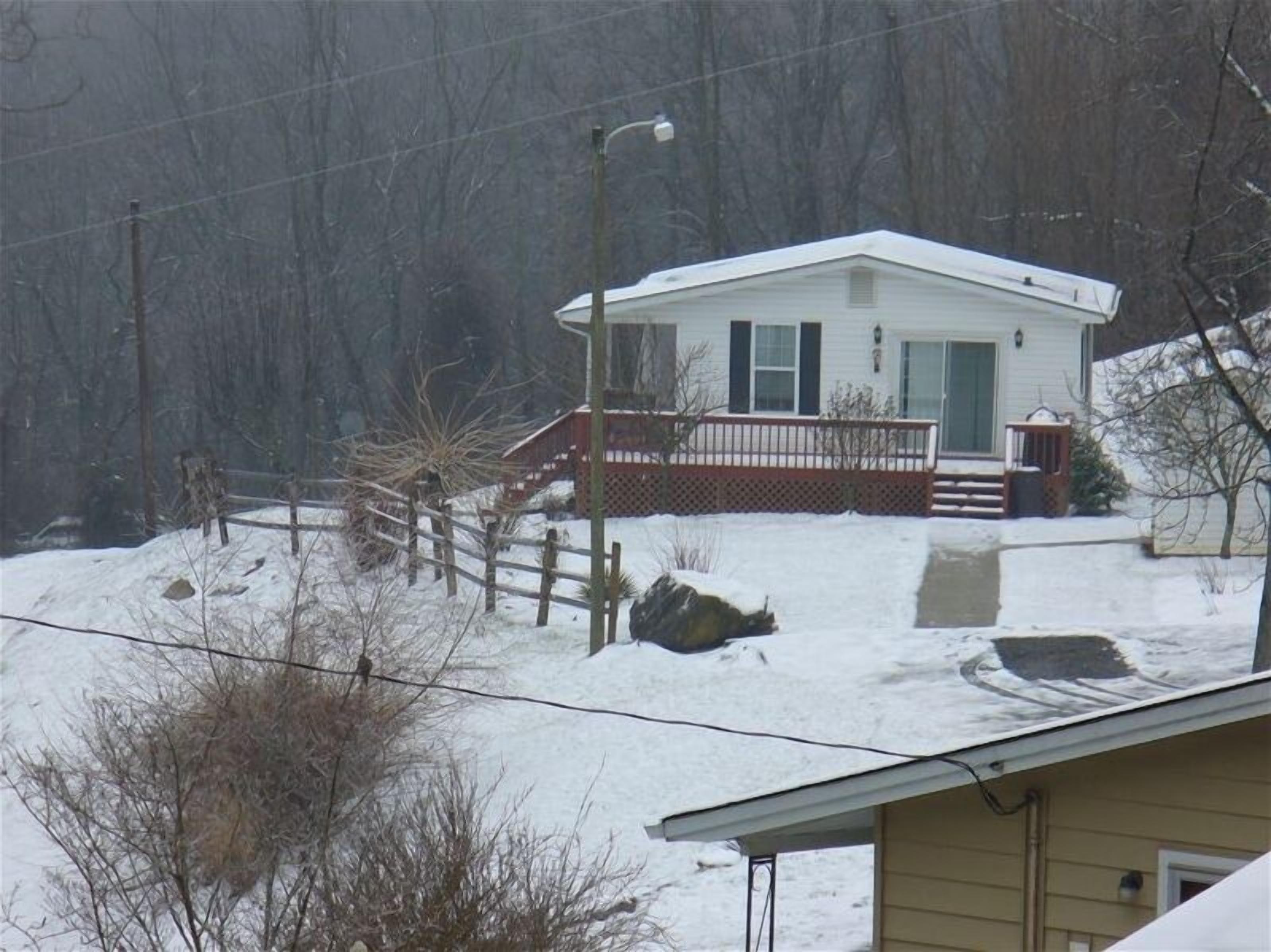A single-story house with a front porch, a small front yard, and a snow-covered roof.