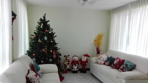 Un salon avec un ensemble de canapés blancs, un sapin de Noël et des décorations festives.
