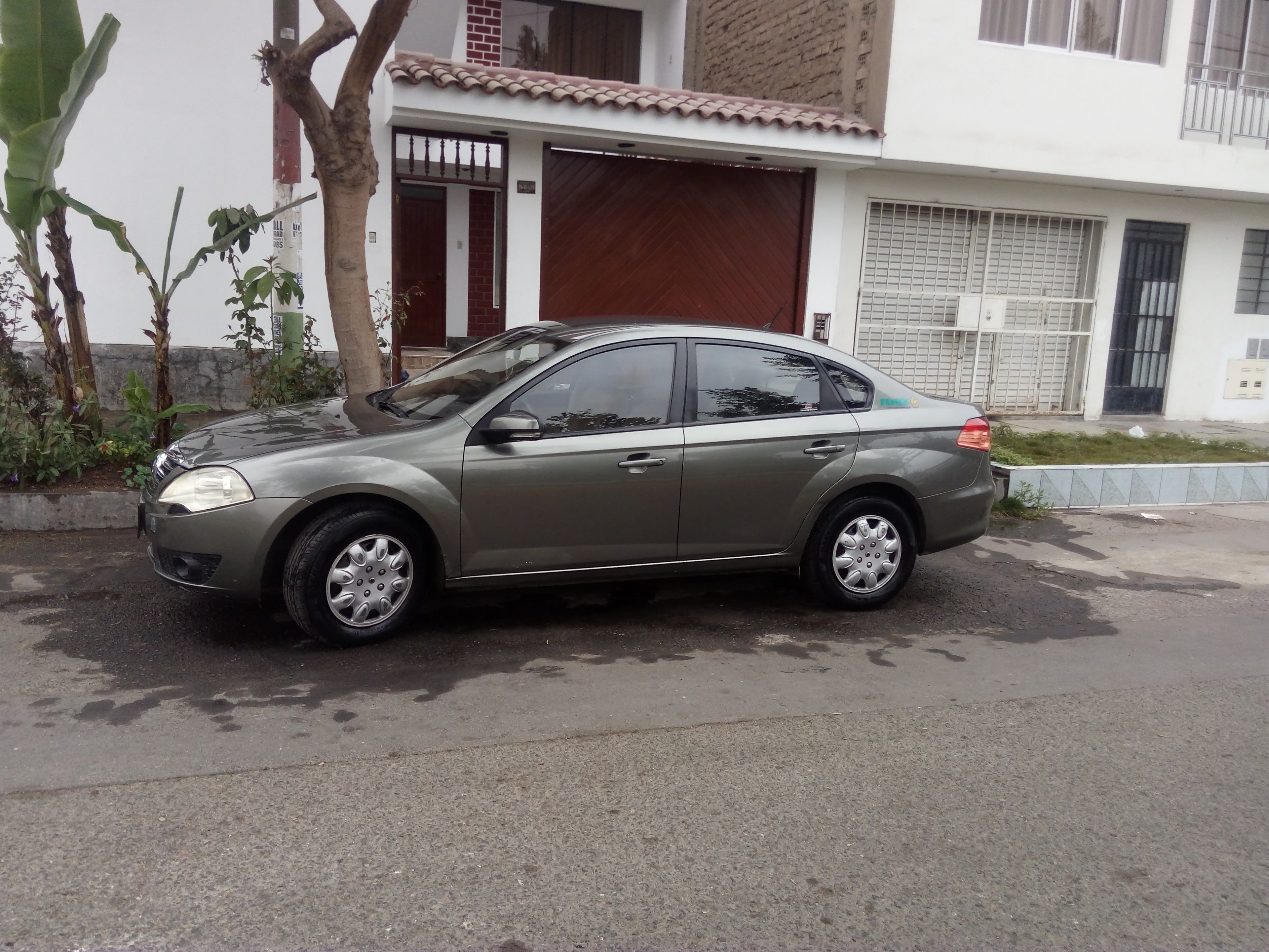 A parked car in front of a building with a tiled roof and a garage door.