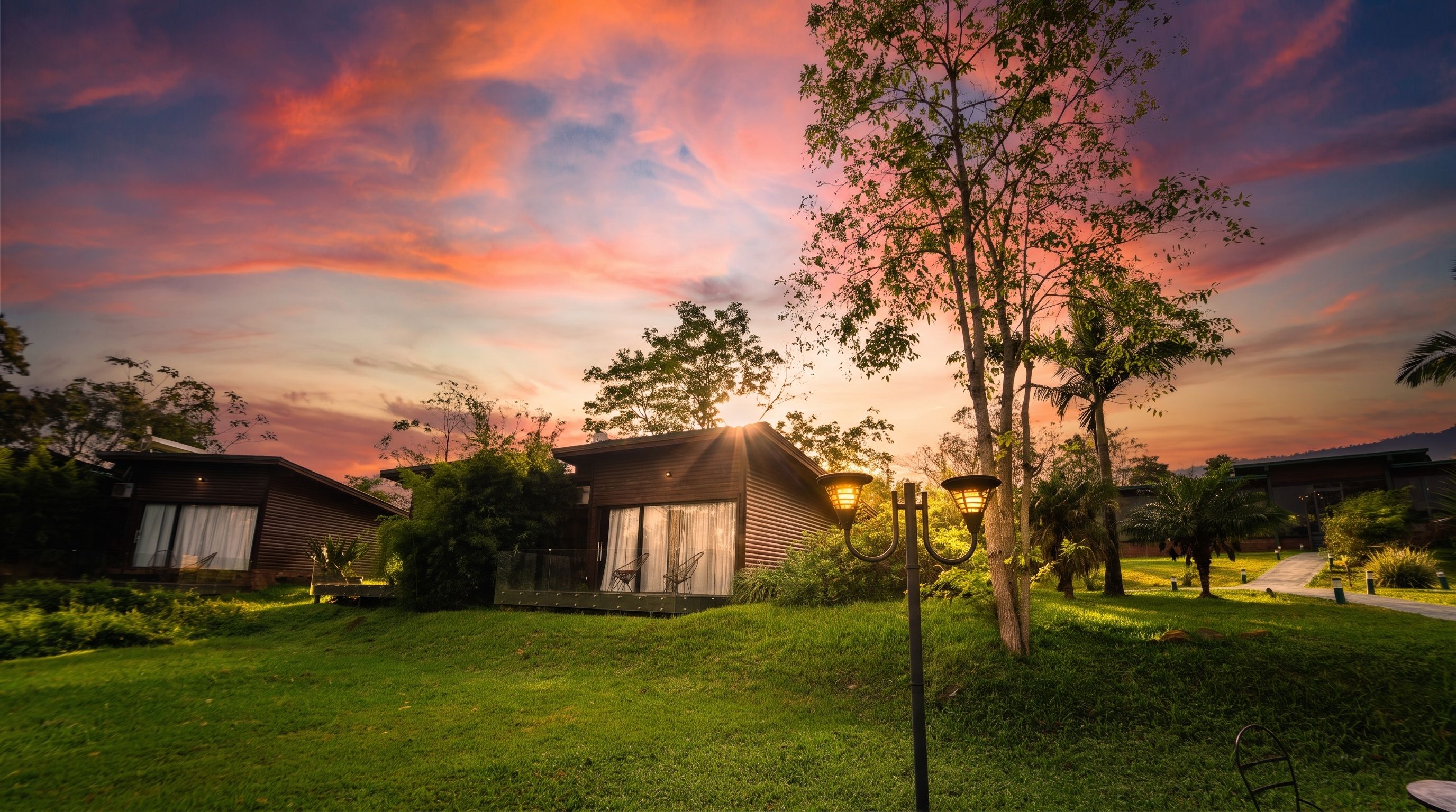 Um bairro residencial com casas, gramado bem cuidado e céu ao pôr do sol.