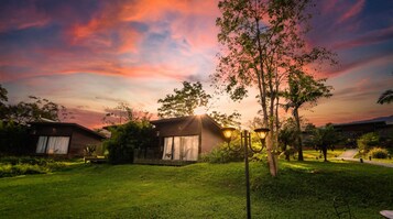 Un barrio residencial con casas, un césped cuidado y un cielo al atardecer.