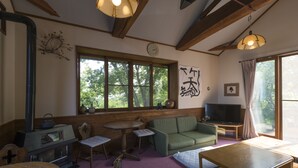 Una habitación acogedora con sofá, televisión, mesa y ventana con vistas a árboles.