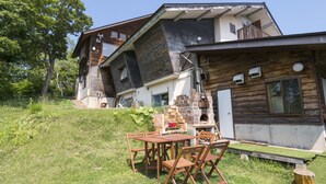 Una casa moderna con fachada de madera, chimenea de ladrillo y comedor con mesa y sillas.