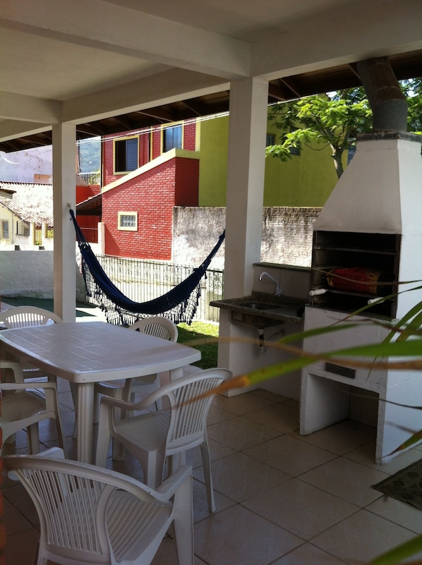 An outdoor patio with a table and chairs, a hammock, and a barbecue grill.