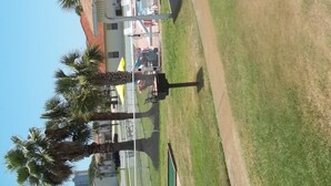 Ein Poolbereich mit umzäuntem Deck, Liegestühlen und Palmen.