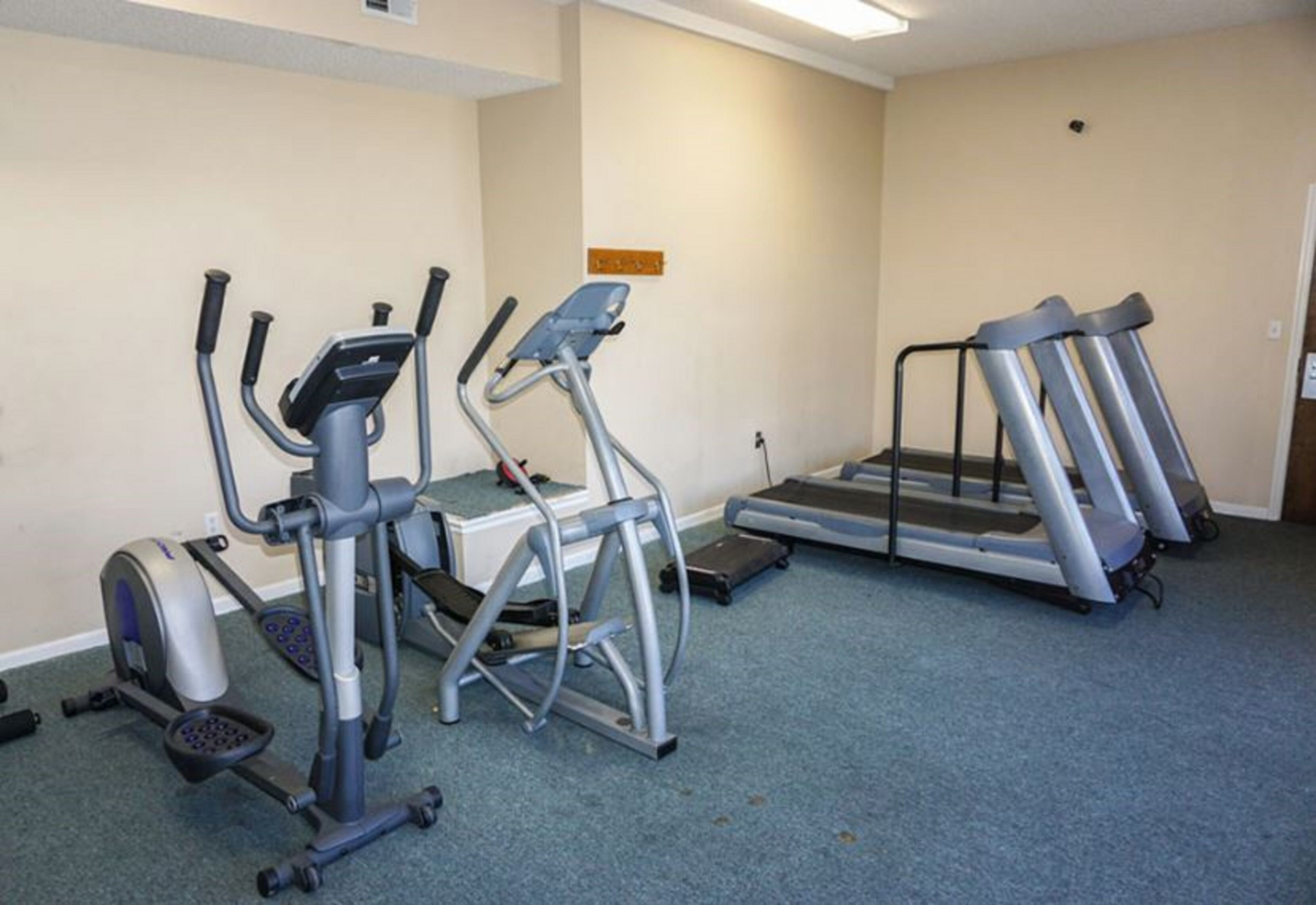 A gym with treadmills, an elliptical, and a stationary bike.