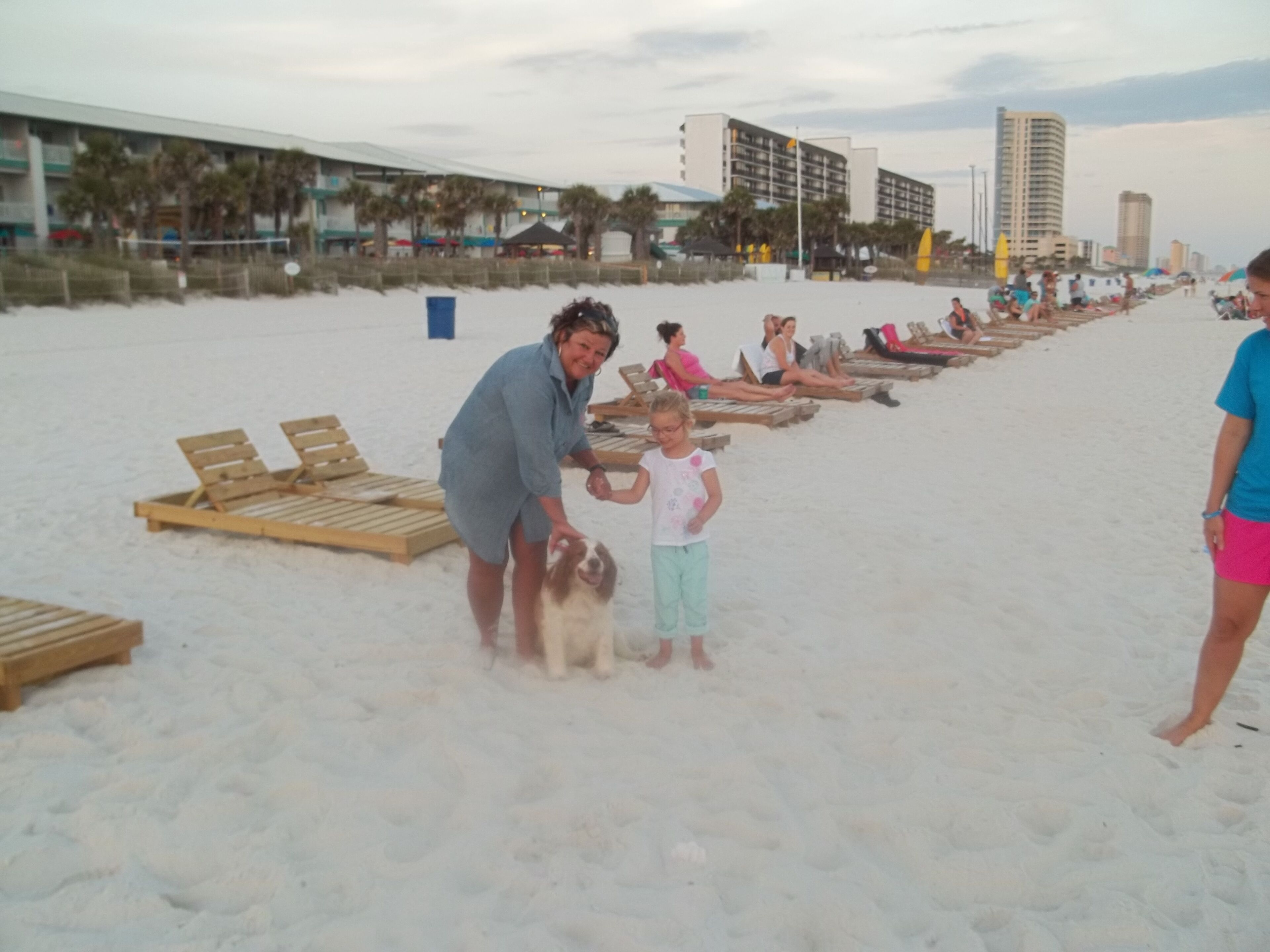 A beach with wooden lounge chairs and a building in the background.