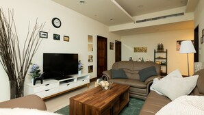 Ein Wohnzimmer mit Fernseher, Sofa, Couchtisch und Dekorationselementen.