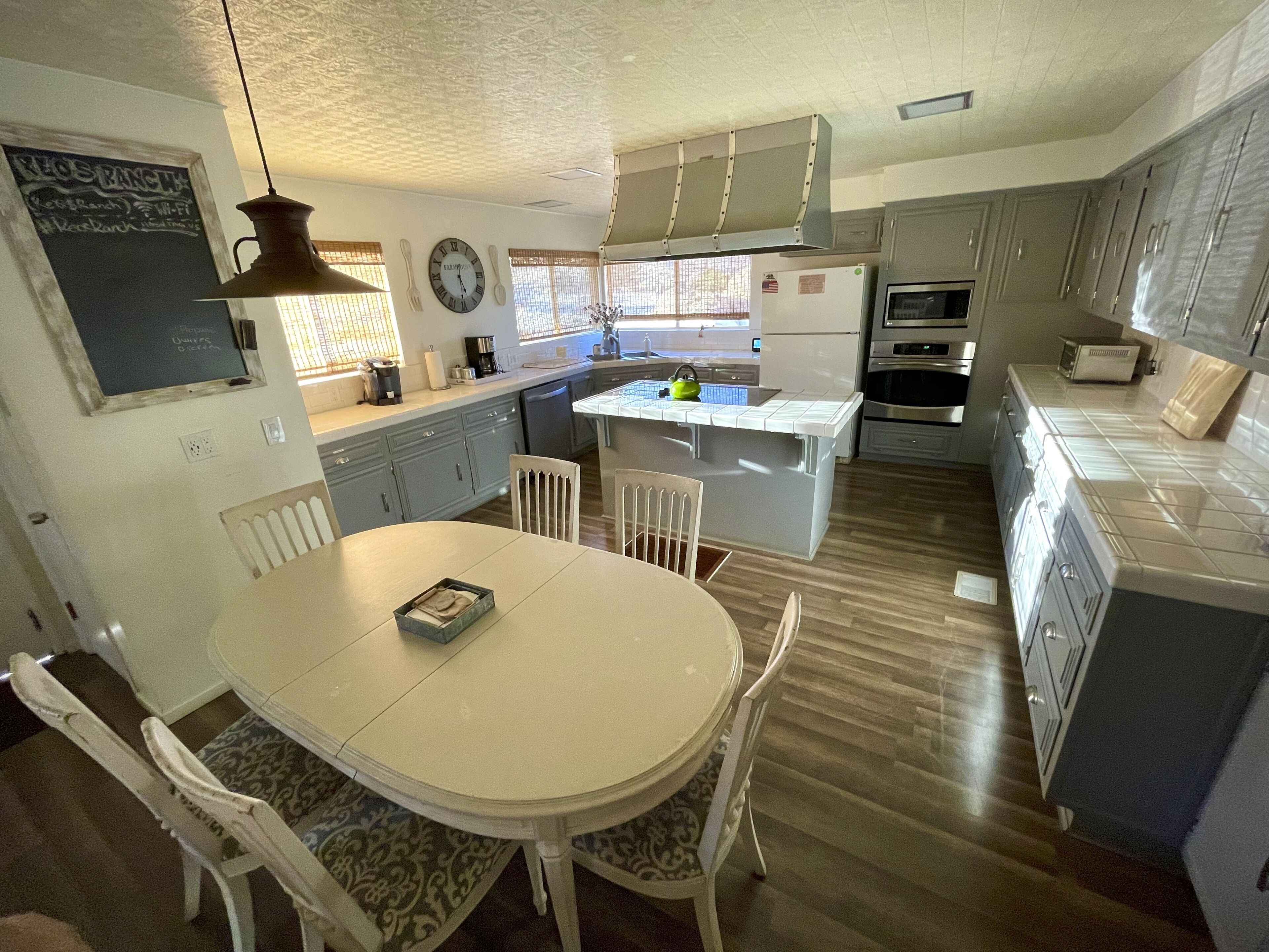 A kitchen with a central island, white cabinetry, and a dining table with chairs.