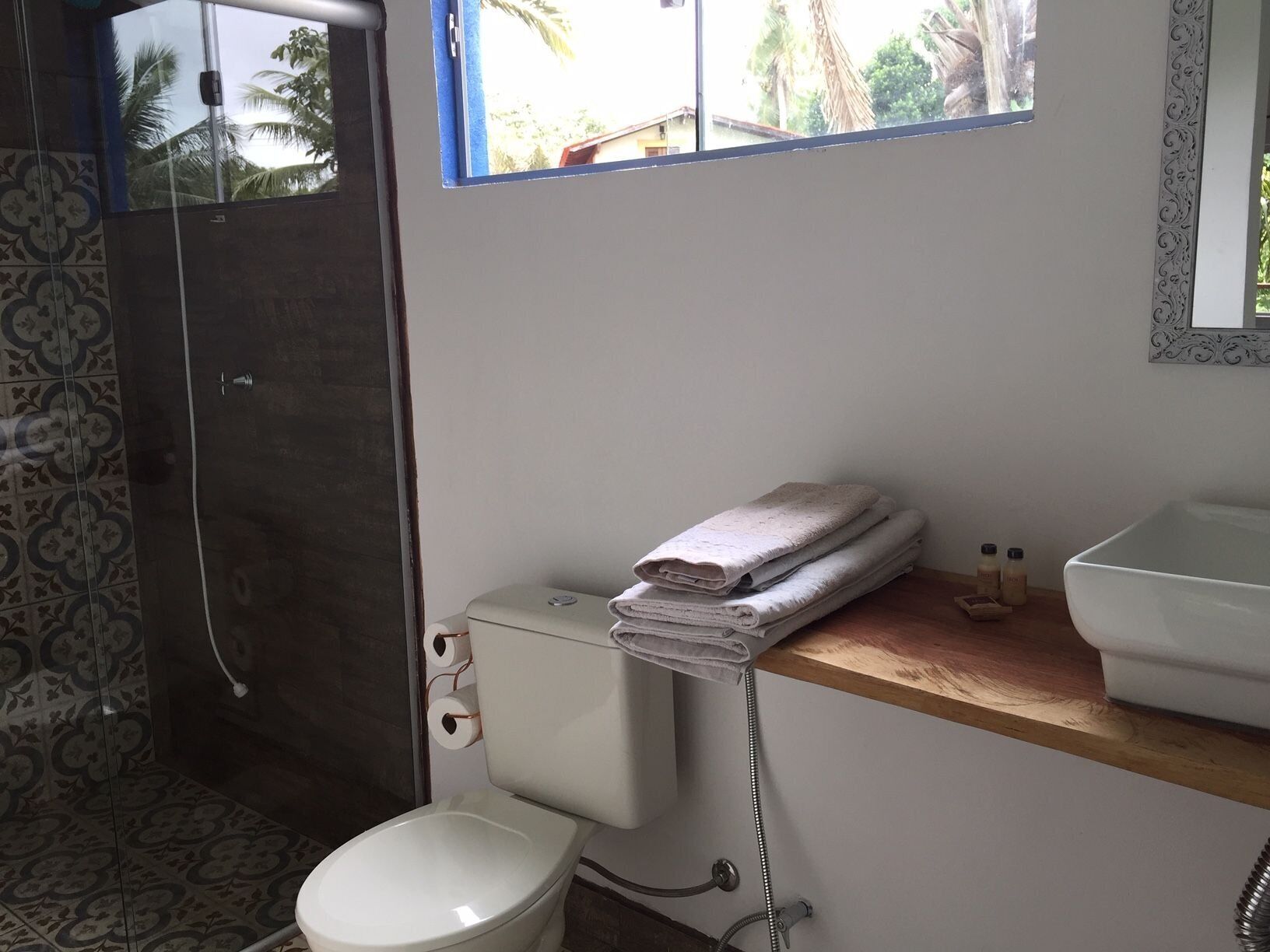 Un baño con inodoro, lavamanos, ducha y ventana.