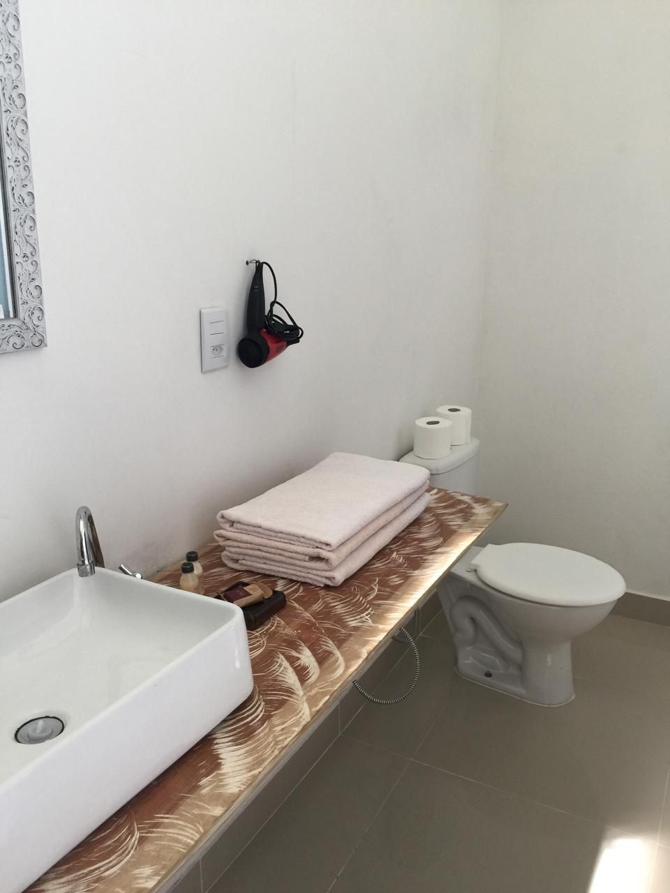 A bathroom with a white sink, a toilet, and a towel rack with folded towels.