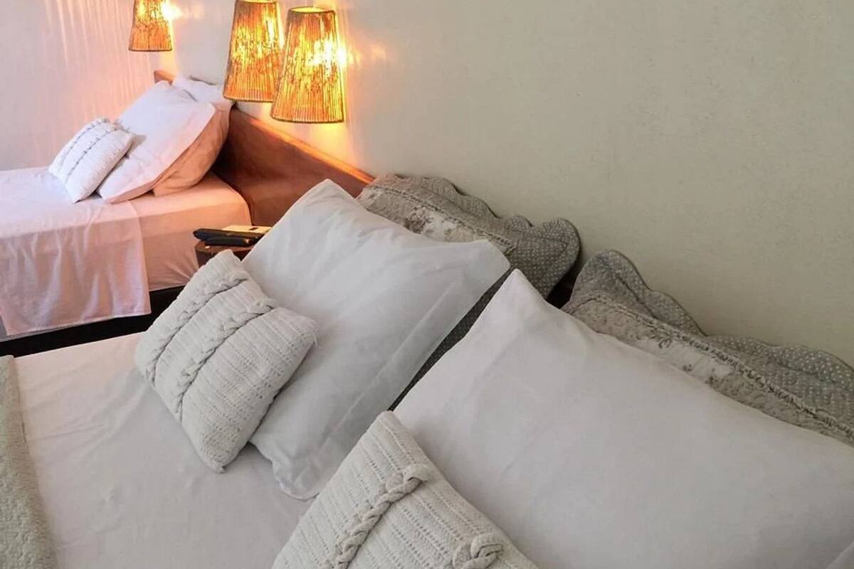 Una habitación de hotel con una cama grande, dos lámparas de noche y una mesita de noche.