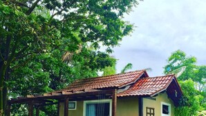 Una casa pequeña de una sola planta con techo de tejas, un porche con baranda de madera y una ventana pequeña.