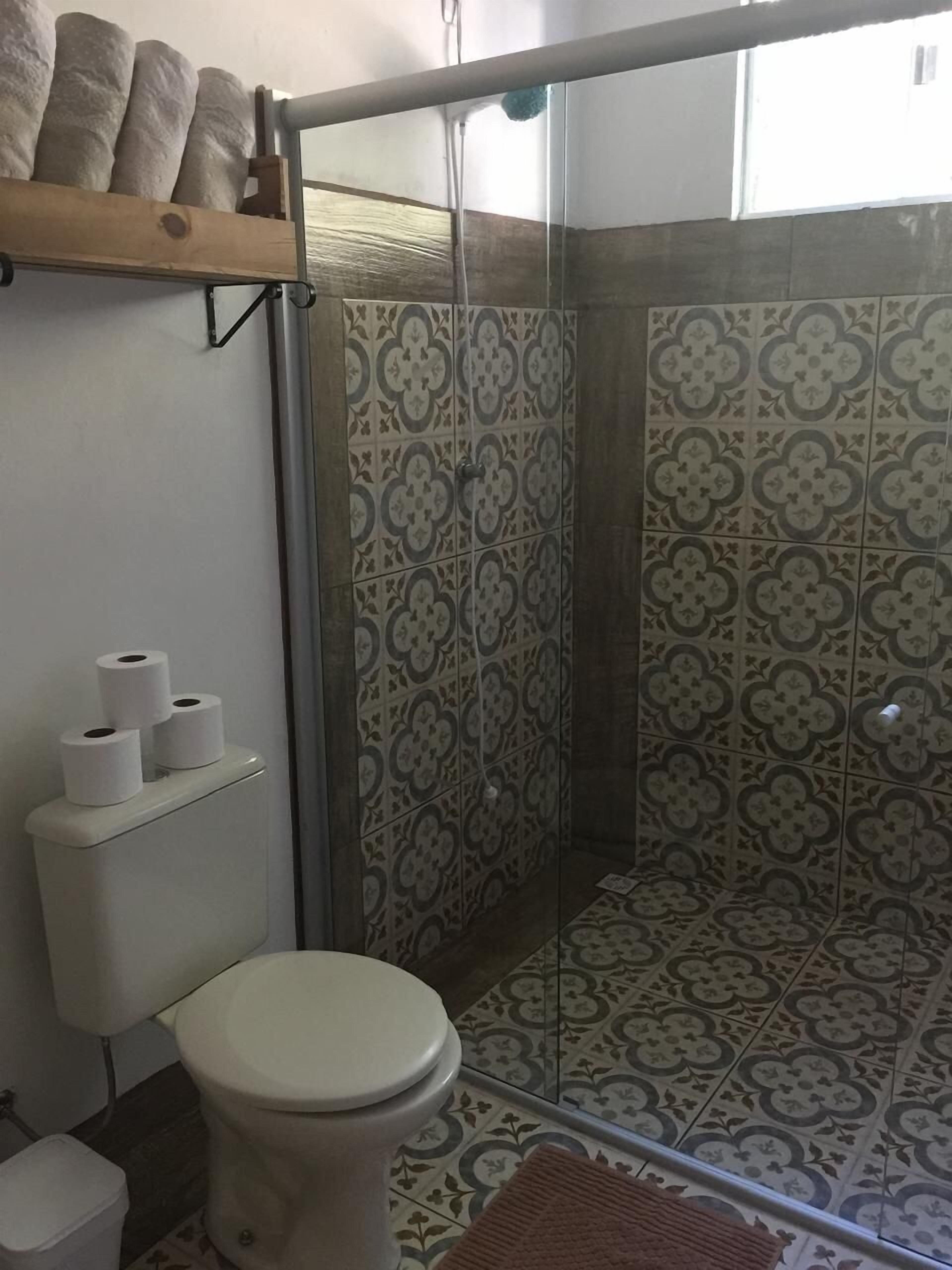 A bathroom with a toilet, a shower enclosure, and patterned tiles.