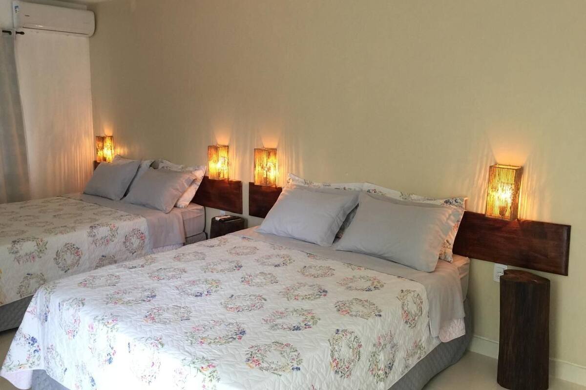 Habitación de hotel con dos camas, cada una con cabecero y lámparas de noche.