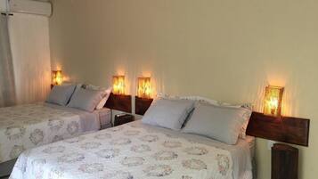 A hotel room with two beds, each with a headboard and bedside lamps.