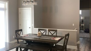 Een eetruimte met een houten tafel, stoelen en een hanglamp.