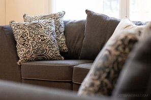 Un canapé marron avec des coussins à motifs et une fenêtre en arrière-plan.