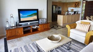 Una sala de estar con televisor, mueble de madera para entretenimiento y un sofá.