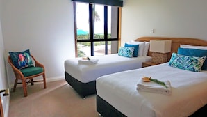 Habitación de hotel con dos camas, una silla y ventana con vista a zonas verdes.