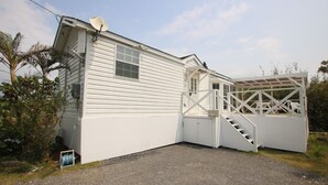 A single-story white mobile home with a covered porch and a small staircase leading to a deck. - cottage NORTH OKINAWA (Nakijin)