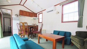 A living room with a wooden table, blue sofas, and a green armchair. - cottage NORTH OKINAWA (Nakijin)