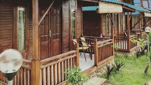 Una cabaña de madera con un porche y un pequeño jardín.