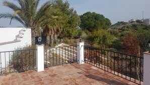 A terrace with a tiled floor, a white railing, and a view of a hillside with trees and a building in the distance. - Torrox campo, country house peaceful location, 10 mins drive from Torrox town (Torrox)