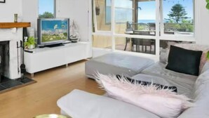 Un salon avec une cheminée, un téléviseur, un canapé et une vue sur l’extérieur.
