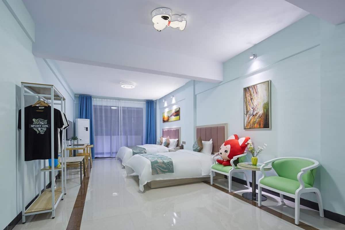 Camera d'albergo con due letti, una scrivania, una sedia, un armadio e un quadro grande appeso al muro.