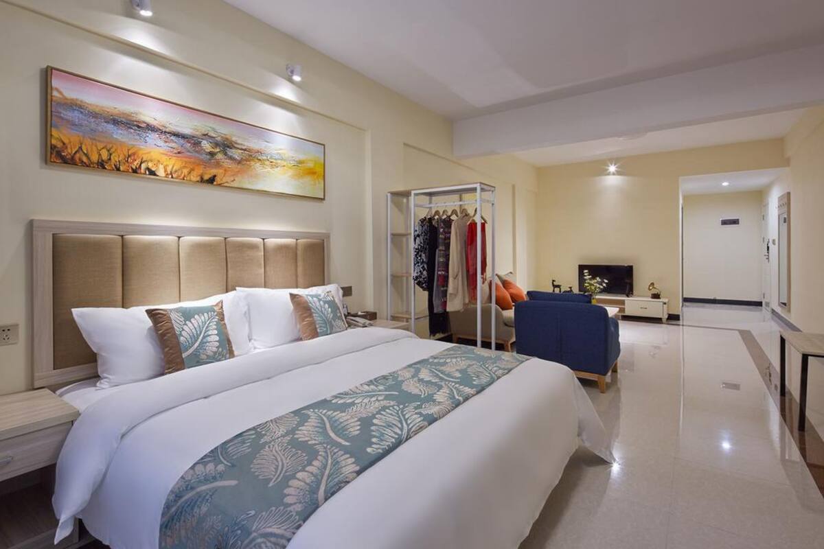 Una camera d'albergo con un letto grande, un armadio, un angolo salotto e una televisione.