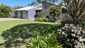 A modern house with a well-maintained lawn, a garage, and a variety of plants and shrubs. - Studio at 60.
Private apartment, close to beaches and cafes. Breakfast included. (Valla Beach)