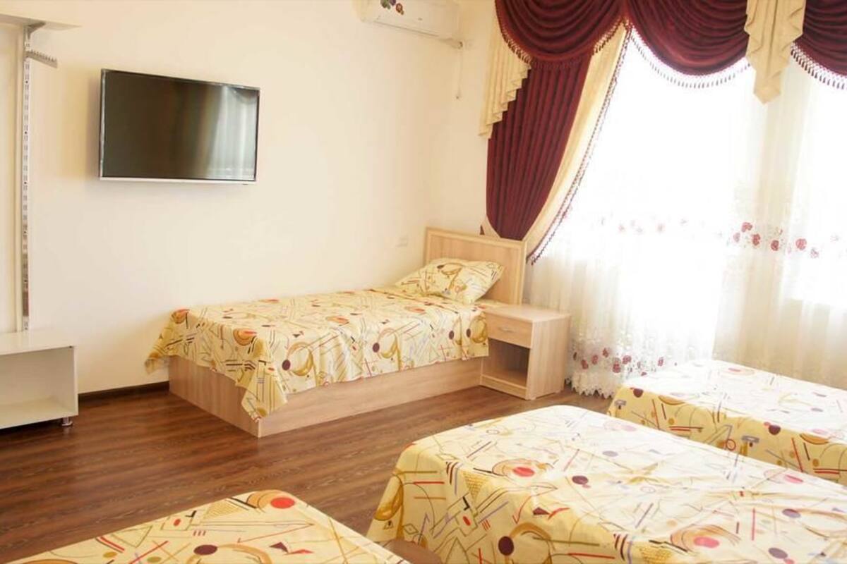 A single bedroom with a bed, bedside table, and a TV mounted on the wall.