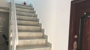 A staircase with a metal railing leading to a landing. A wooden door is visible to the right.