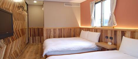 A hotel room with two beds, wooden paneling, a TV, and a window with curtains.