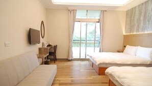 Habitación de hotel con dos camas, un sofá, un escritorio con una silla y un televisor.