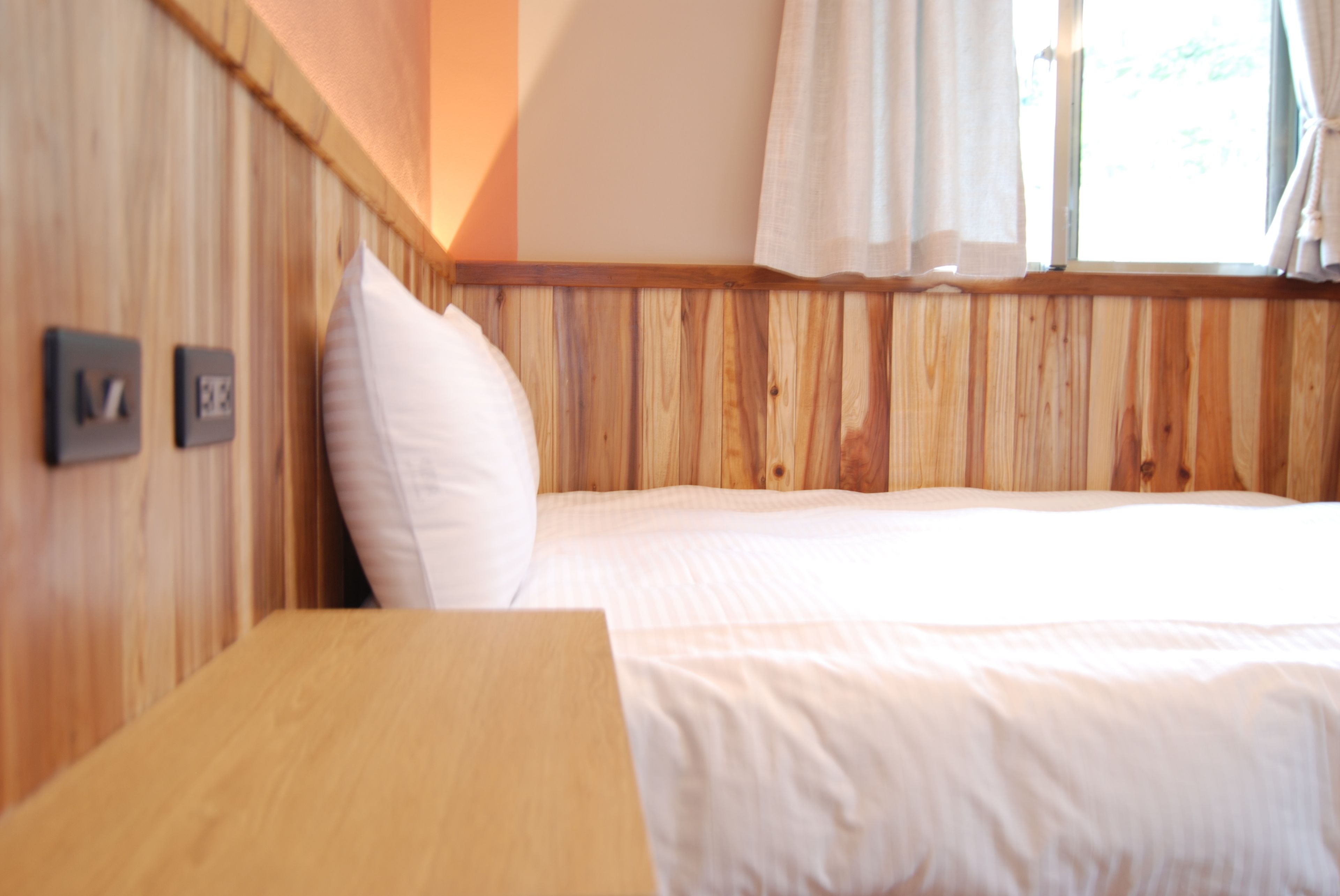 A wooden-paneled room with a bed, a wooden table, and a window with curtains.
