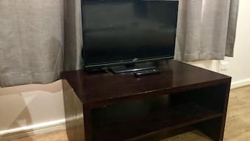 Un meuble TV en bois foncé, sur lequel est posée une télévision à écran plat et une télécommande.