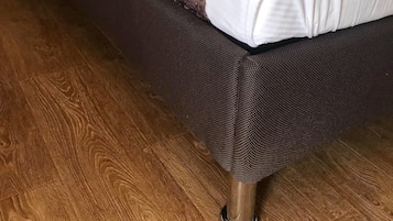 Un lit avec une tête de lit sombre, des oreillers blancs et une couverture à motifs.