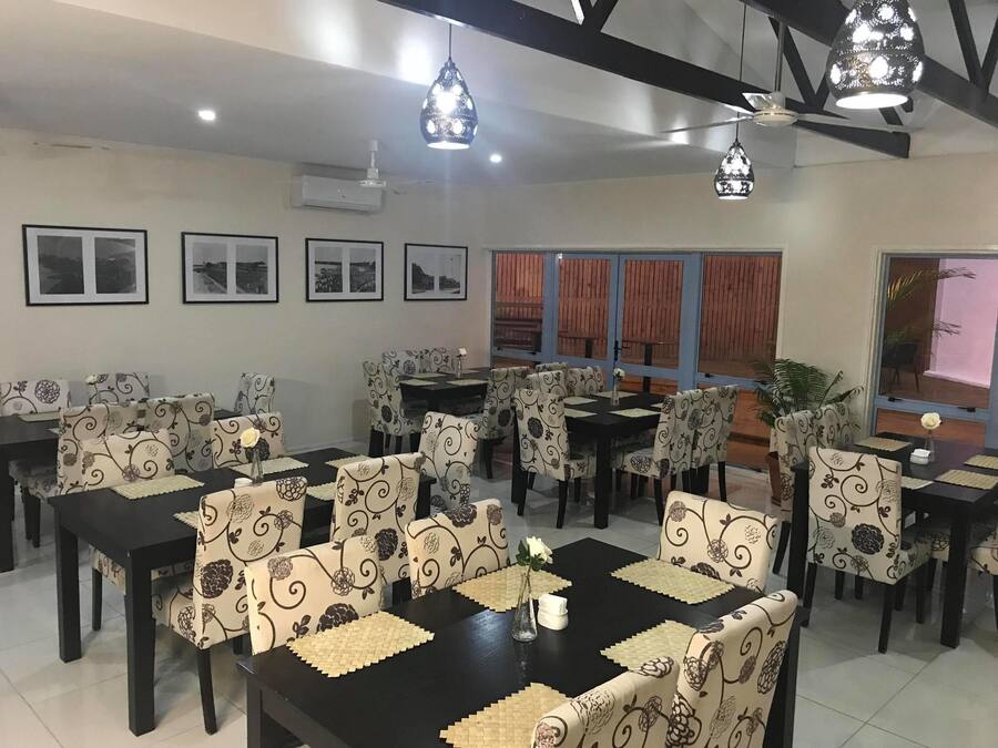 A dining area with multiple tables and chairs, air conditioning units, and framed pictures on the walls.