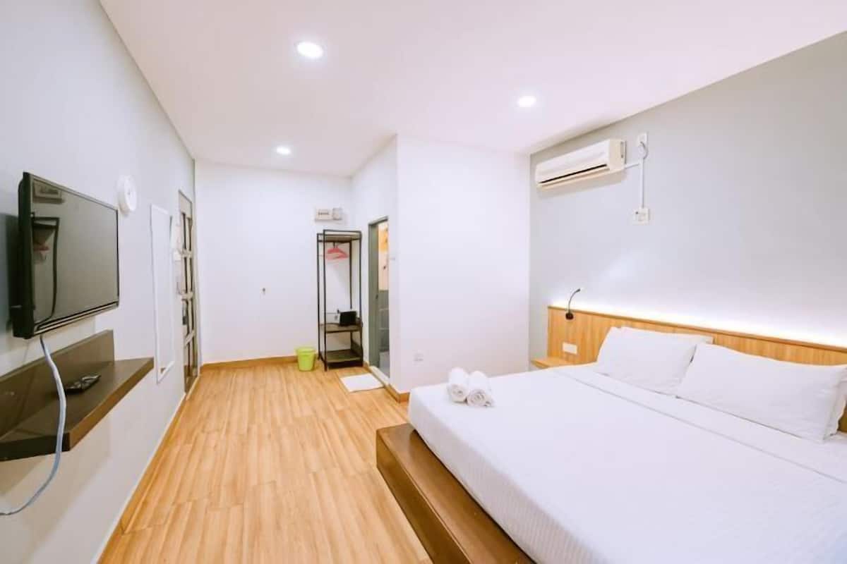 A hotel room with a bed, a TV, a desk, and a bathroom.