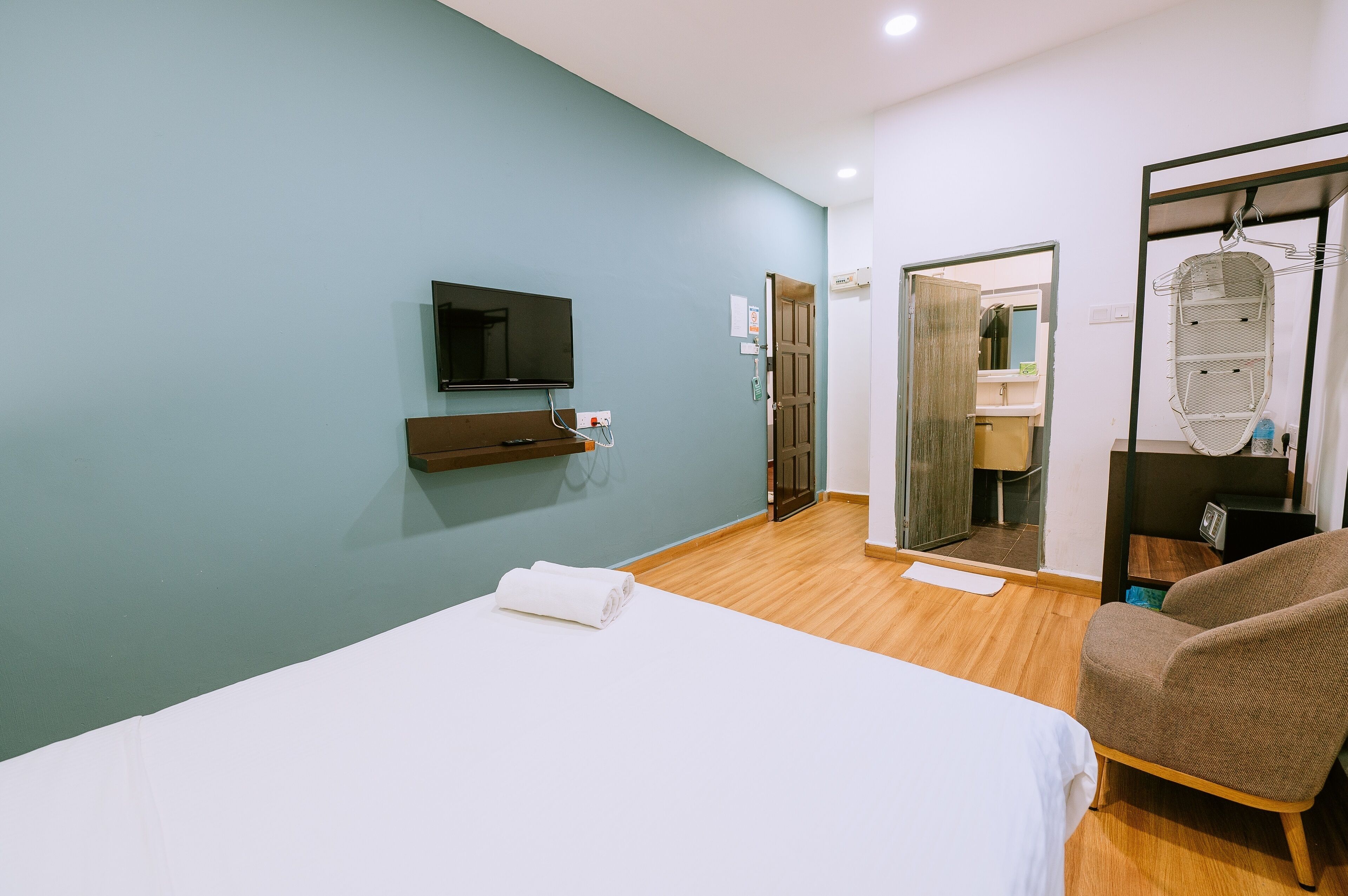 Une chambre d’hôtel avec un lit, une télévision, un miroir et une chaise.