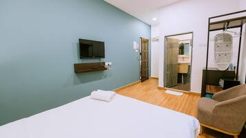 Une chambre d’hôtel avec un lit, une télévision, un miroir et une chaise.