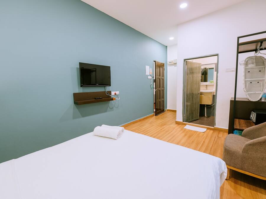 Une chambre d’hôtel avec un lit, une télévision, un miroir et une chaise.
